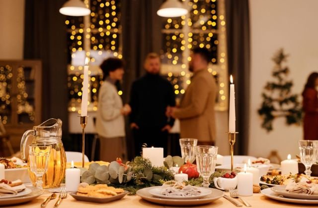 Família reunida em torno da mesa de ceia de Natal com velas e luzes ao fundo