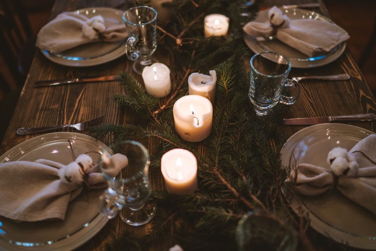 Mesa de Natal com pratos, guardanapos amarrados, velas e ramos de pinheiro