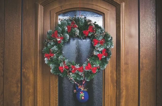 Guirlanda de Natal com laços vermelhos pendurada em uma porta de madeira