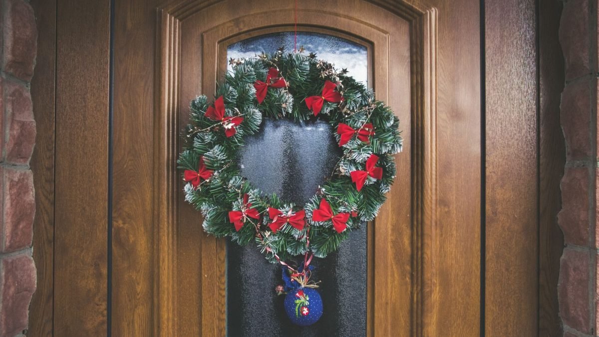 Guirlanda de Natal com laços vermelhos pendurada em uma porta de madeira