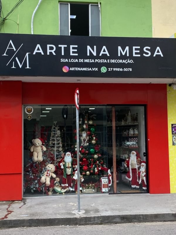 Fachada da loja Arte na Mesa com vitrine decorada para o Natal, com árvore e Papais Noéis
